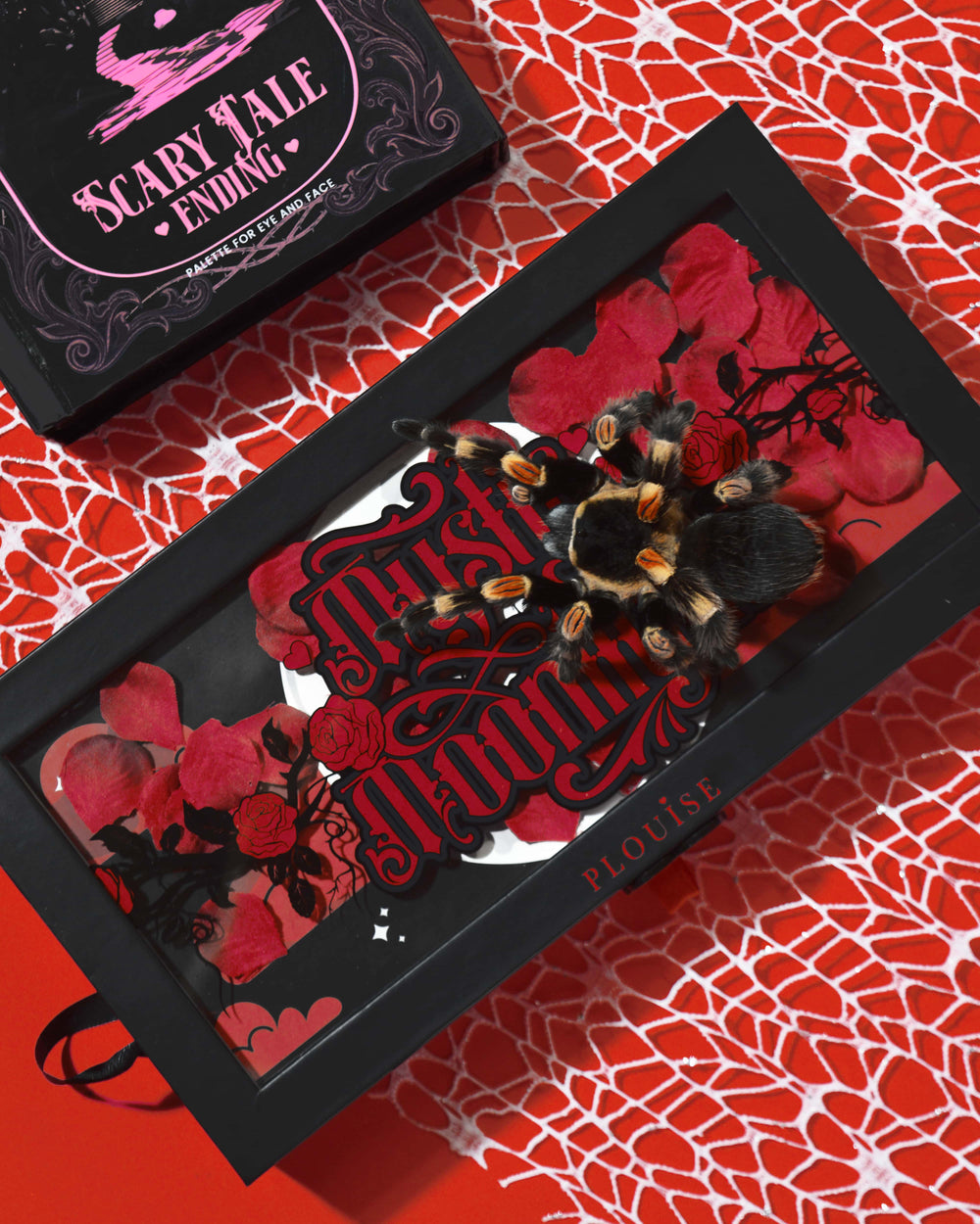 Pudełko z paletą cieni do powiek P.Louise Mystic Moonlight Halloween pokryte płatkami czerwonych róż i tarantulą na czerwonym tle pajęczej sieci