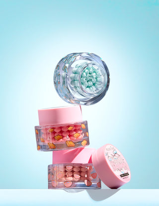 Three small jars with colourful vitamin c capsule in a gel on a light blue background