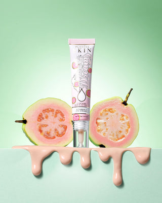 Tube of P. Louise Dose Of Dreams Vitamin C Brightening Eye Cream surround by guava fruit on a green background
