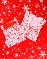 Pair of pink and white striped pyjamas with red festive bow designs set on a red background with snowflakes