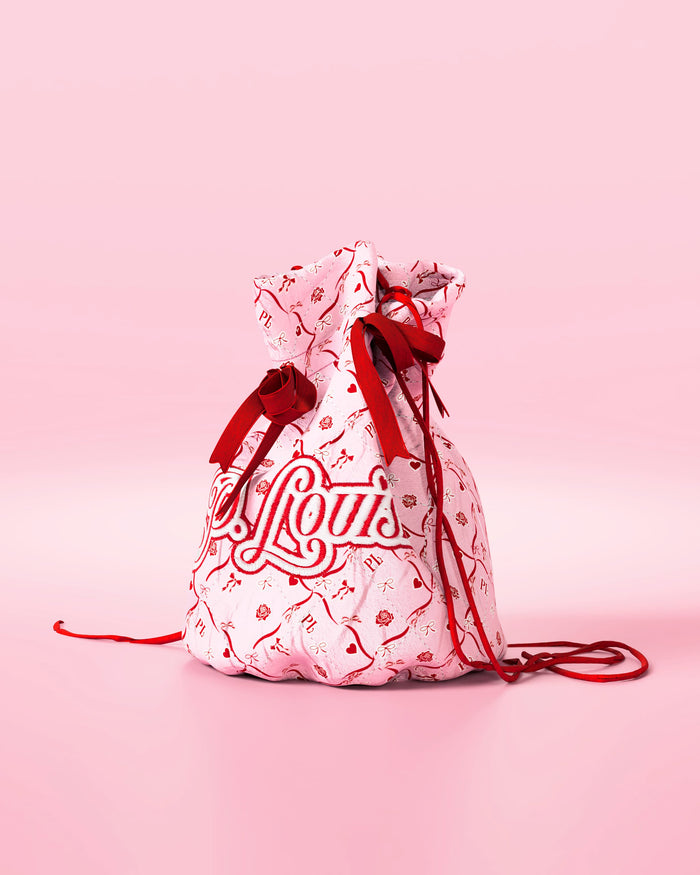 Pink drawstring bag with red bows and a festive design with 'P.Louis' branding on a pink background