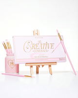 Zamknięta różowa paleta cieni do powiek P.Louise Creative Comeback XXXL Rainbow umieszczona na sztaludze artystycznej otoczonej pędzlami do makijażu