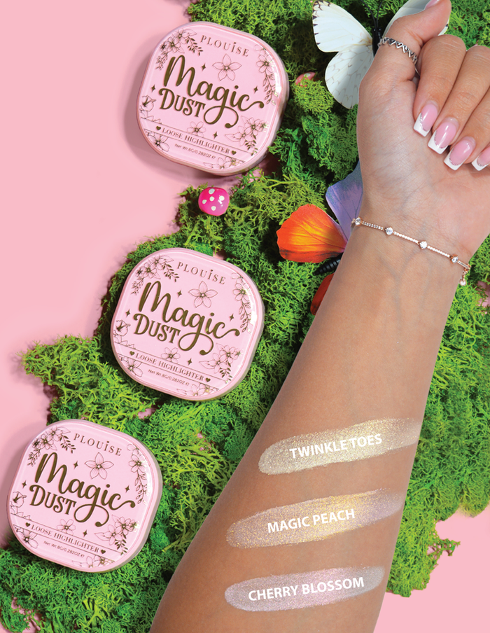 Trzy kompaktowe, sypkie rozświetlacze oznaczone Magic Dust w odcieniach Twinkle Toes, Magic Peach i Cherry Blossom, umieszczone na ramieniu z kwiatowym tłem.