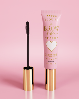 P.Louise Fluffy Soap Brow Balm Instant Fix product in a pink tube with a golden cap, accompanied by a black eyebrow brush, displayed against a pink background.