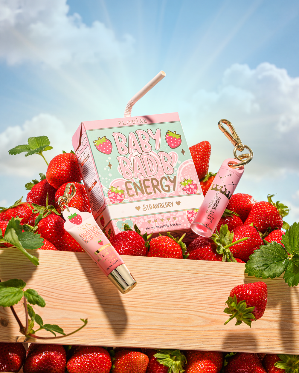 P.Louise Strawberry Baby Bad B Mini olejek do ust i mini odżywka do ust na stole otoczonym truskawkami