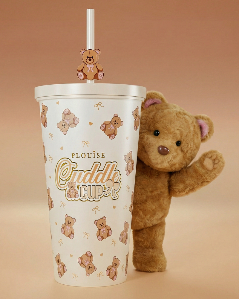 Zdjęcie kubka i słomki ze stalowym kubkiem do przytulania P.Louise Teddy Bear, za którym macha niedźwiedź