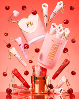 Różowy zestaw upominkowy XL Protect Your Pout, otwarty w otoczeniu wiśni oraz różowo-czerwonych odżywek do ust na różowym tle