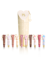 Zestaw tubek z odżywką do ust P.Louise Protect Your Pout Lips w różnych odcieniach, ułożonych przed wysokim, cylindrycznym etui w kolorze kremowym, z suwakiem w kształcie serca. Do każdej tuby dołączony jest mały złoty brelok do kluczy.
