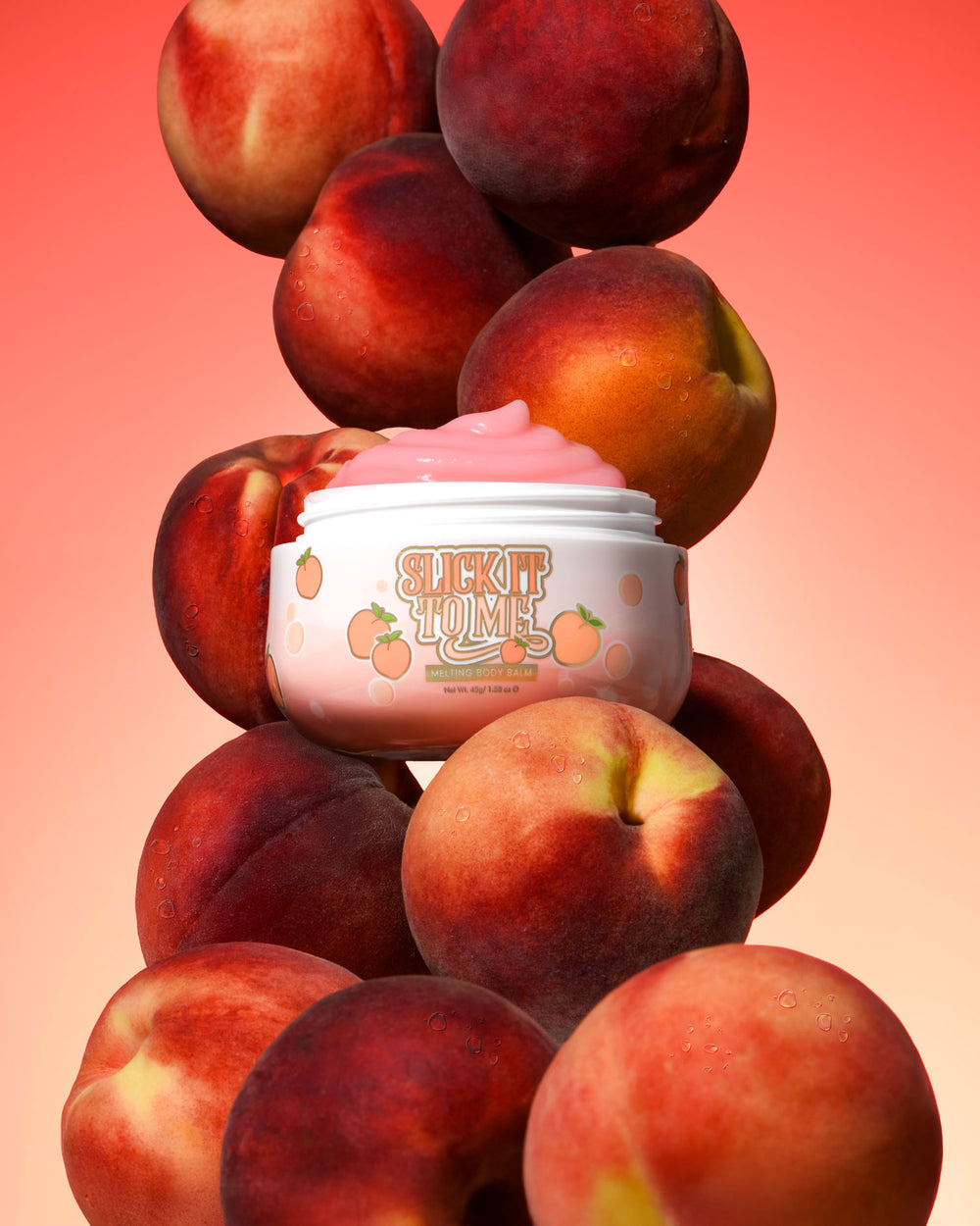 Słoik P. Louise Slick It To Me Peach Melting Balsam do ciała z różowym kremem w otoczeniu brzoskwiń na gradientowym tle