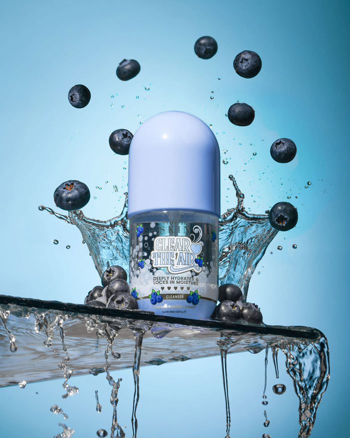 Butelka P. Louise Clear The Air Blueberry Gel Cleanserl otoczona jagodami i rozpryskami wody na niebieskim tle