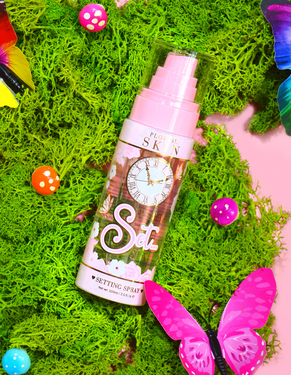 Butelka P. Louise Ready Set Slay Long Lasting Setting Spray otoczona elementami dekoracyjnymi, w tym kolorowym sztucznym mchem, motylami i grzybami.